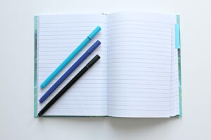 lined notebook with 3 blue pens