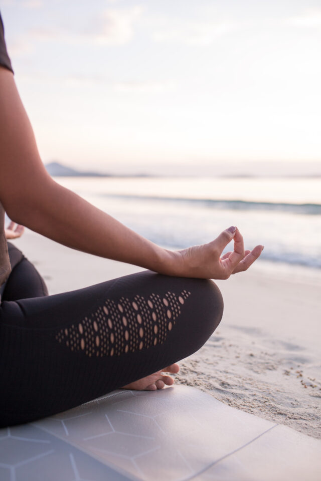 getting started with yoga - woman meditating on the beach