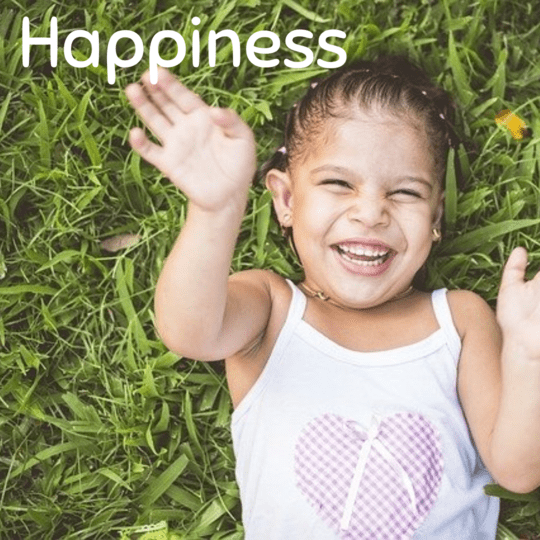 7 traits of happy people - small girl laughing in grass