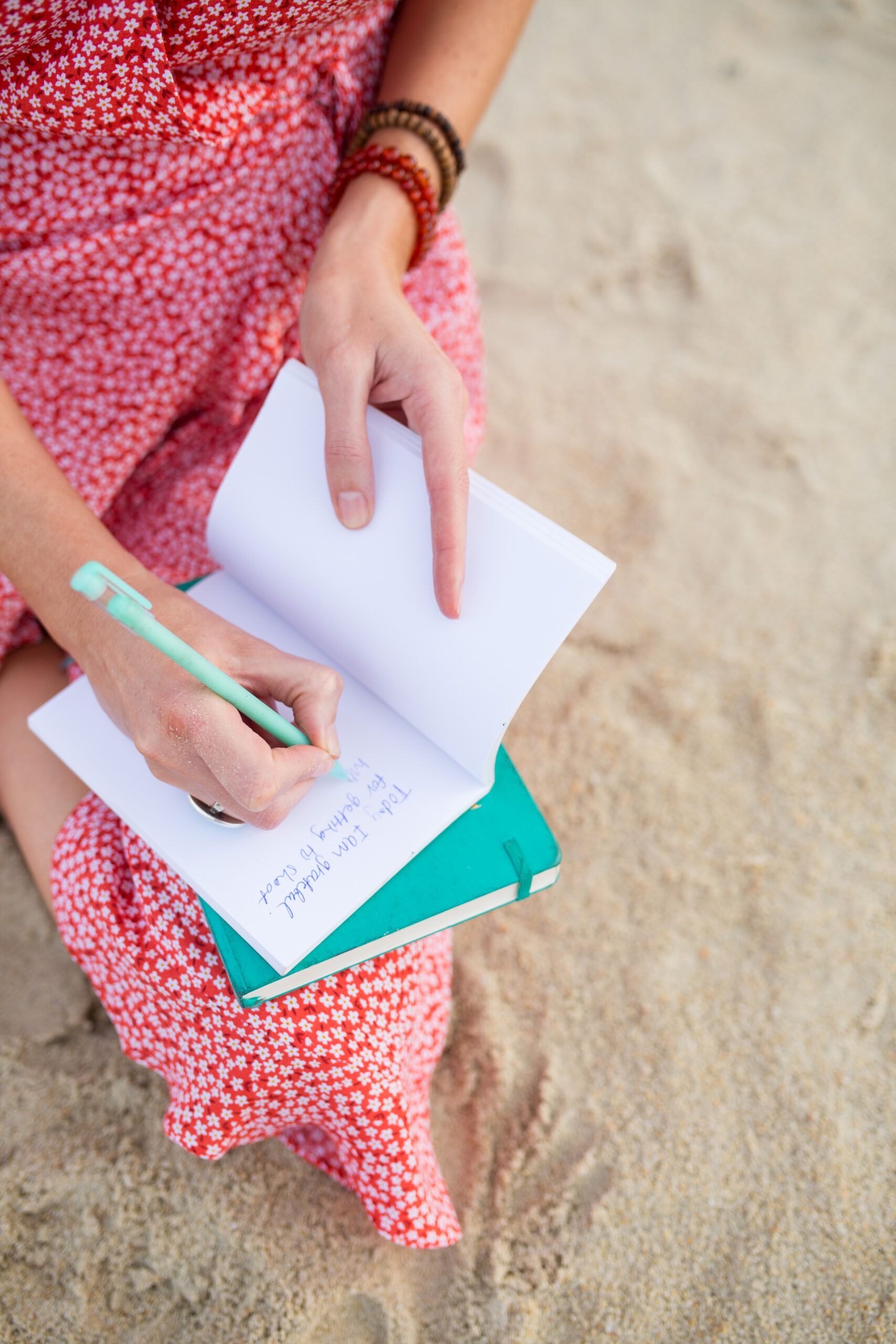 woman sitting on the beach writing in a journal