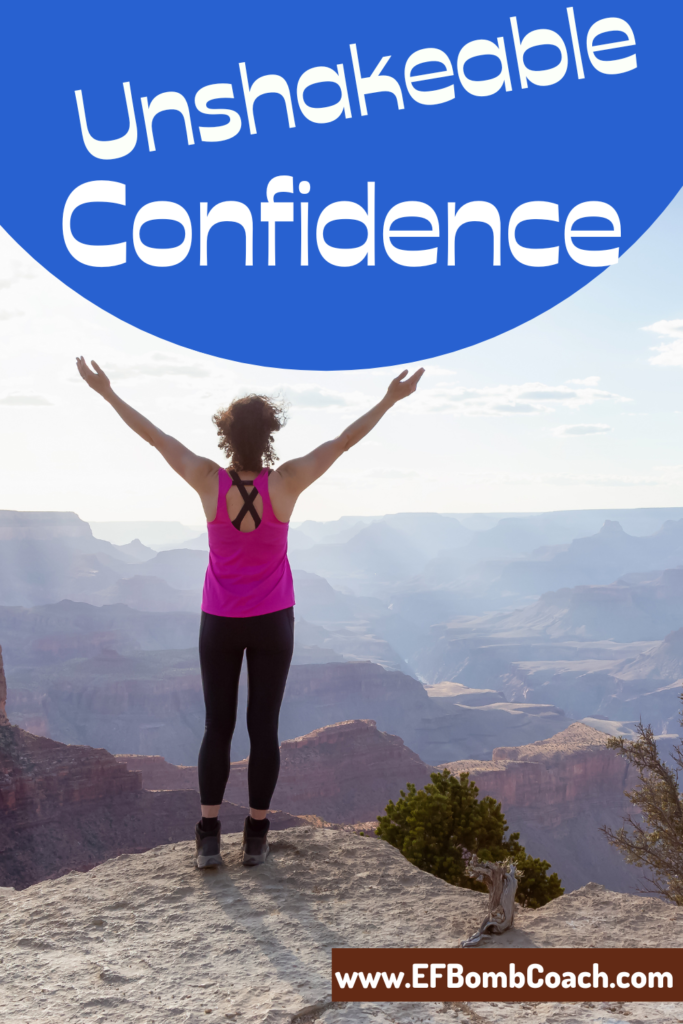 unshakeable confidence - woman standing on cliff arms raised