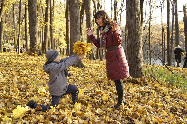 mother and son in the woods- son is giving his mom a bouquet of fallen leaves