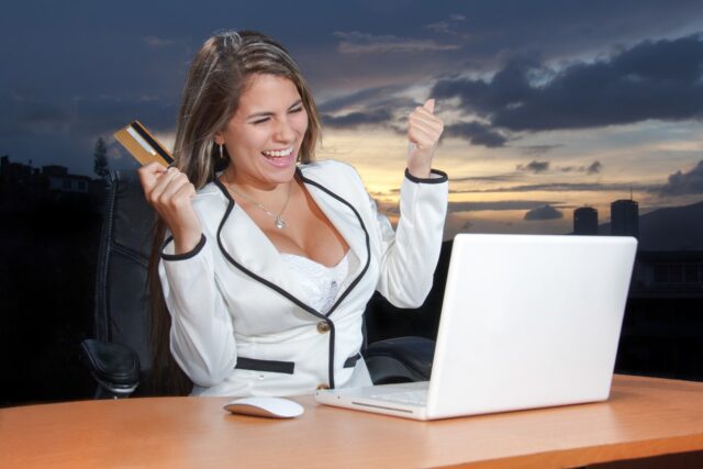 woman withe credit card smiling at her laptop